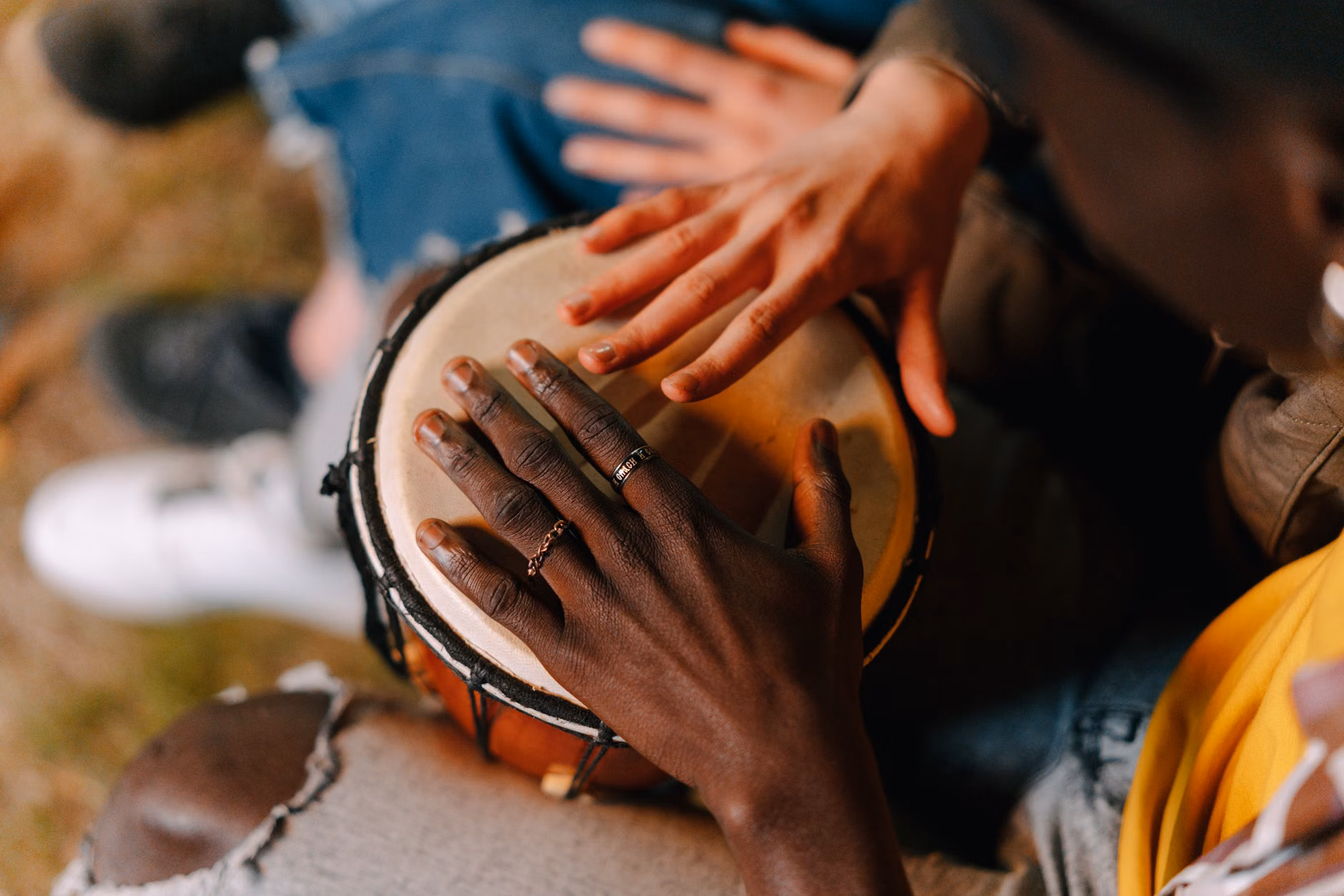 The Power of Rhythm: How Drumming Circles Enhance Wellbeing for Older Adults 1 Close-up of hands playing a djembe drum during a drumming workshop.