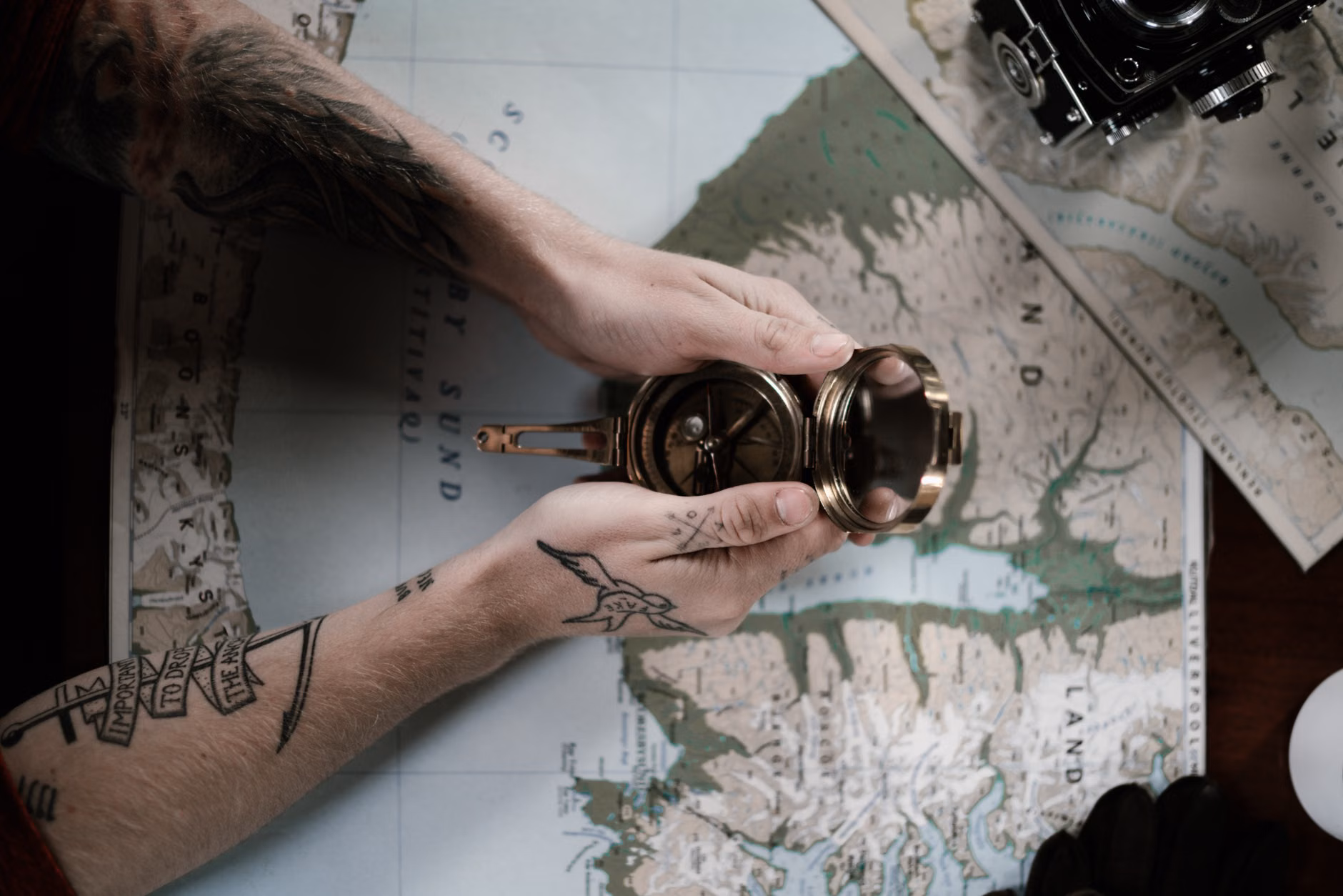 Hands using a brass drafting compass on a paper map.