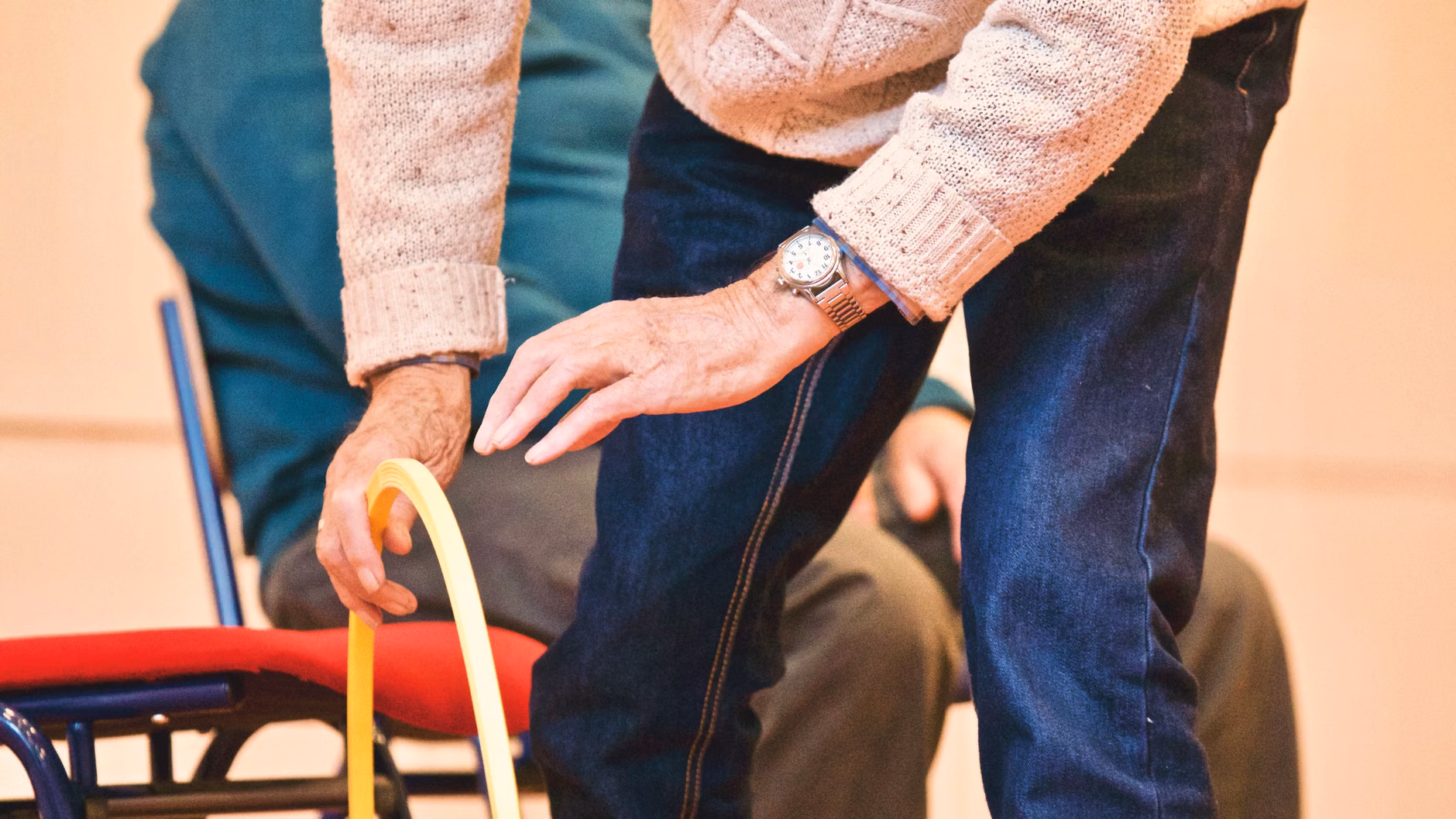 Close-up of an older adult's leg engaged during a seated knee-extension exercise.