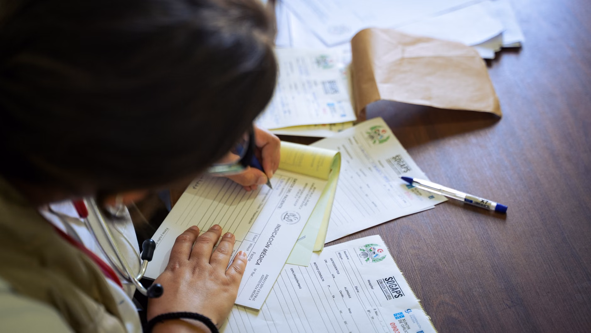 An older adult organizing health documentation at a home desk.
