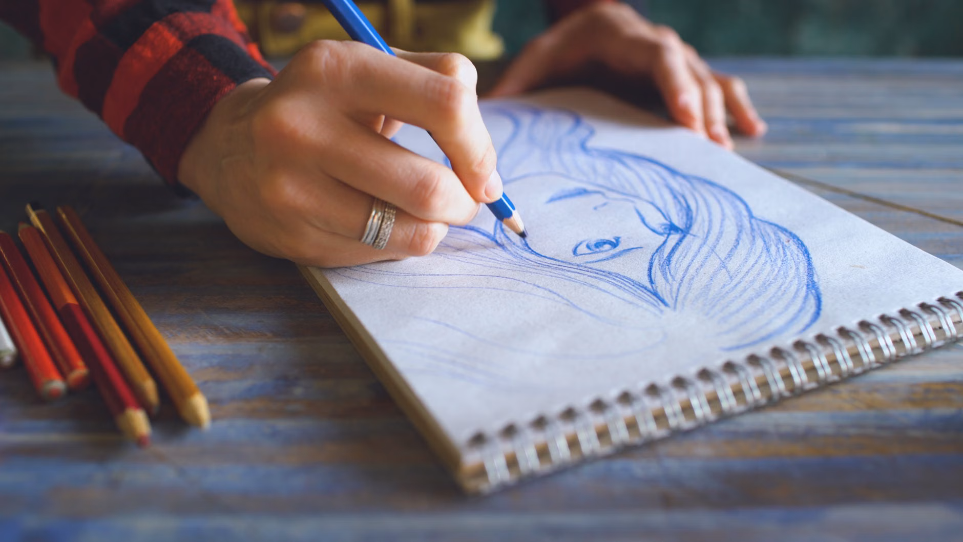 The Art of Mindful Bird-Sketching: A Practical Guide to Focus and Flow 1 Close-up of hands sketching a bird in a notebook.