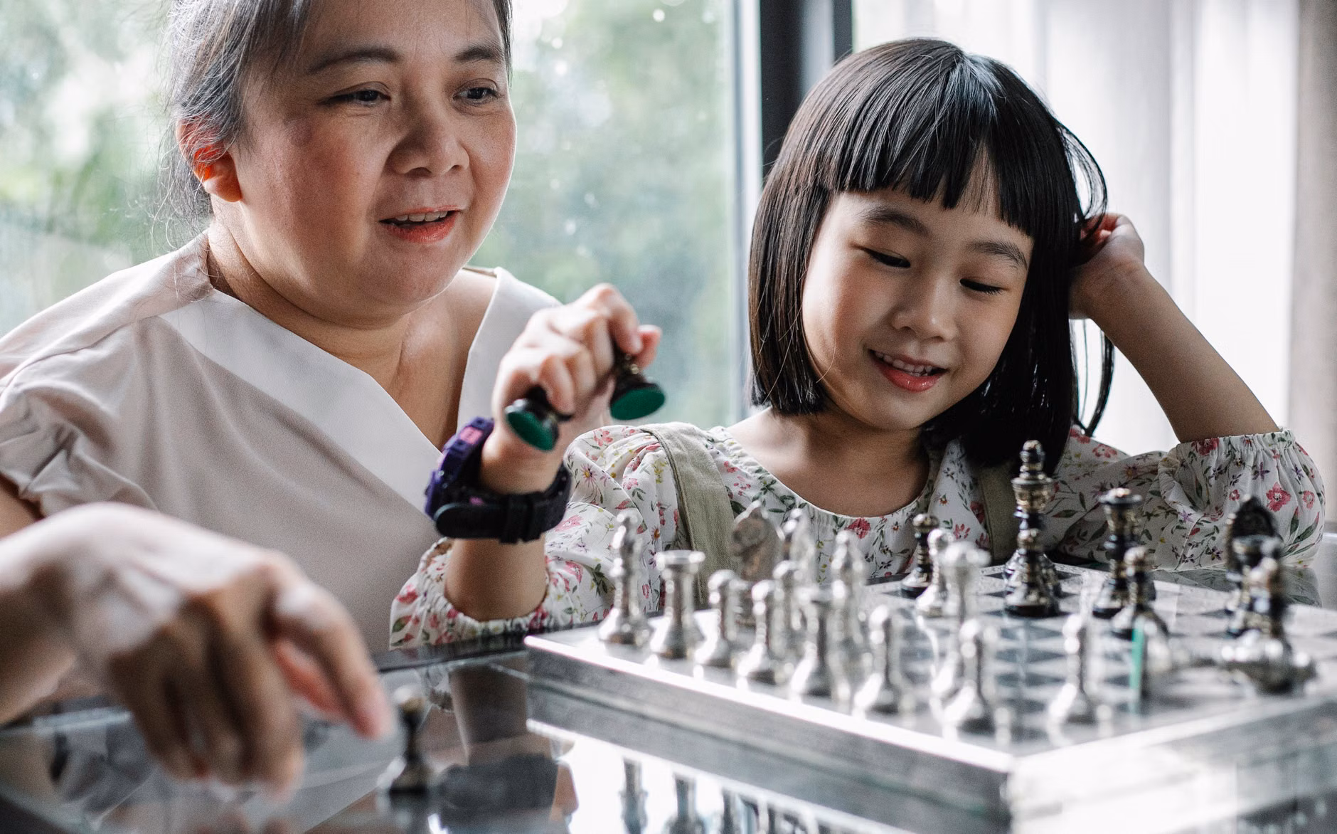 An older adult teaching chess strategy to a peer.