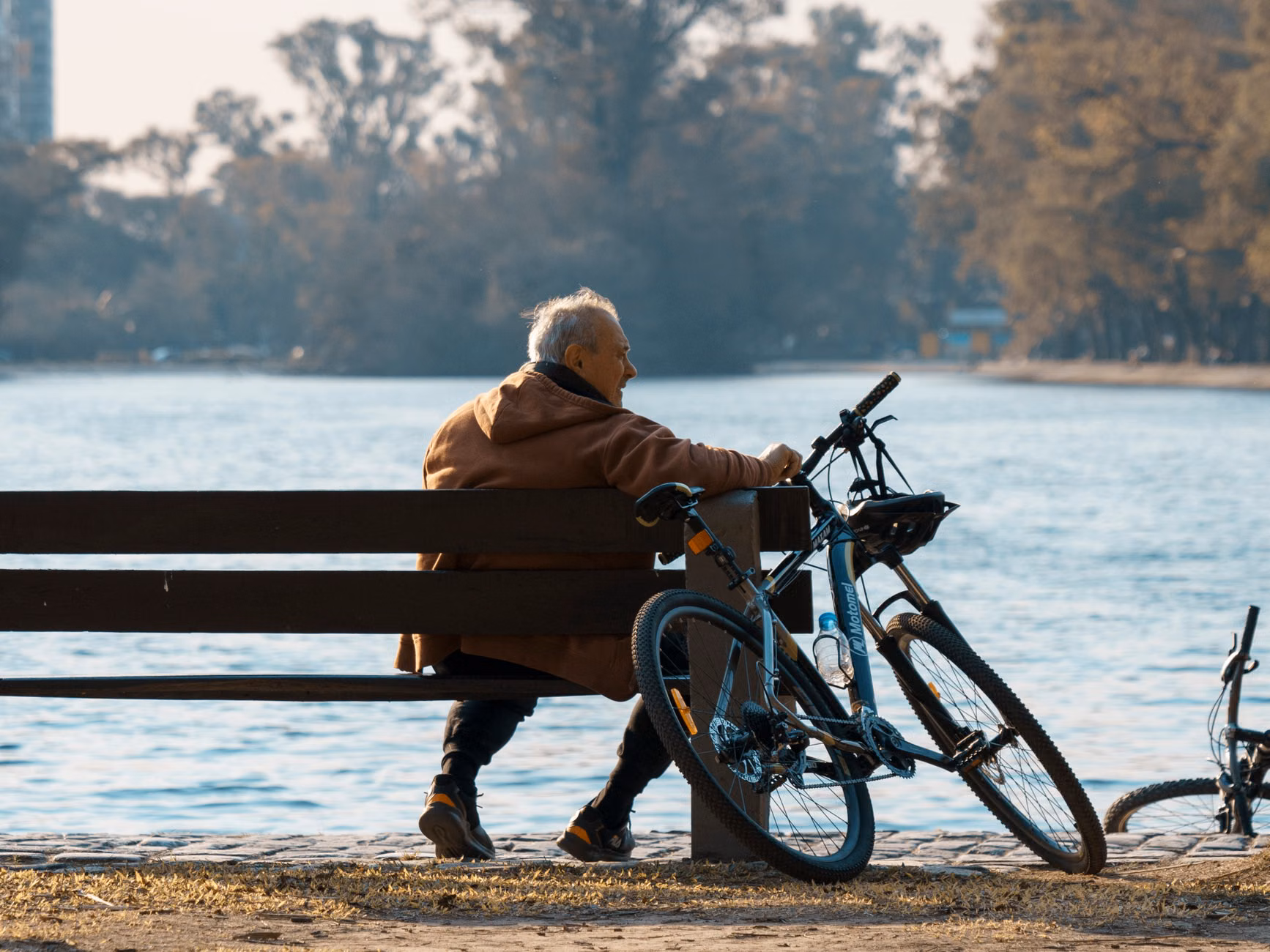 A senior traveler resting on a bench by a river while checking a digital map.