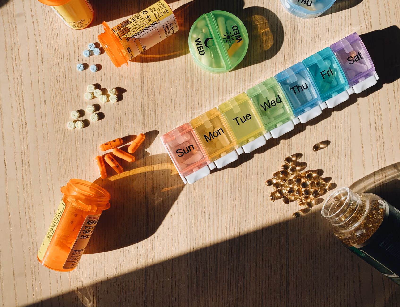 A weekly medication and supplement organizer on a wooden table.