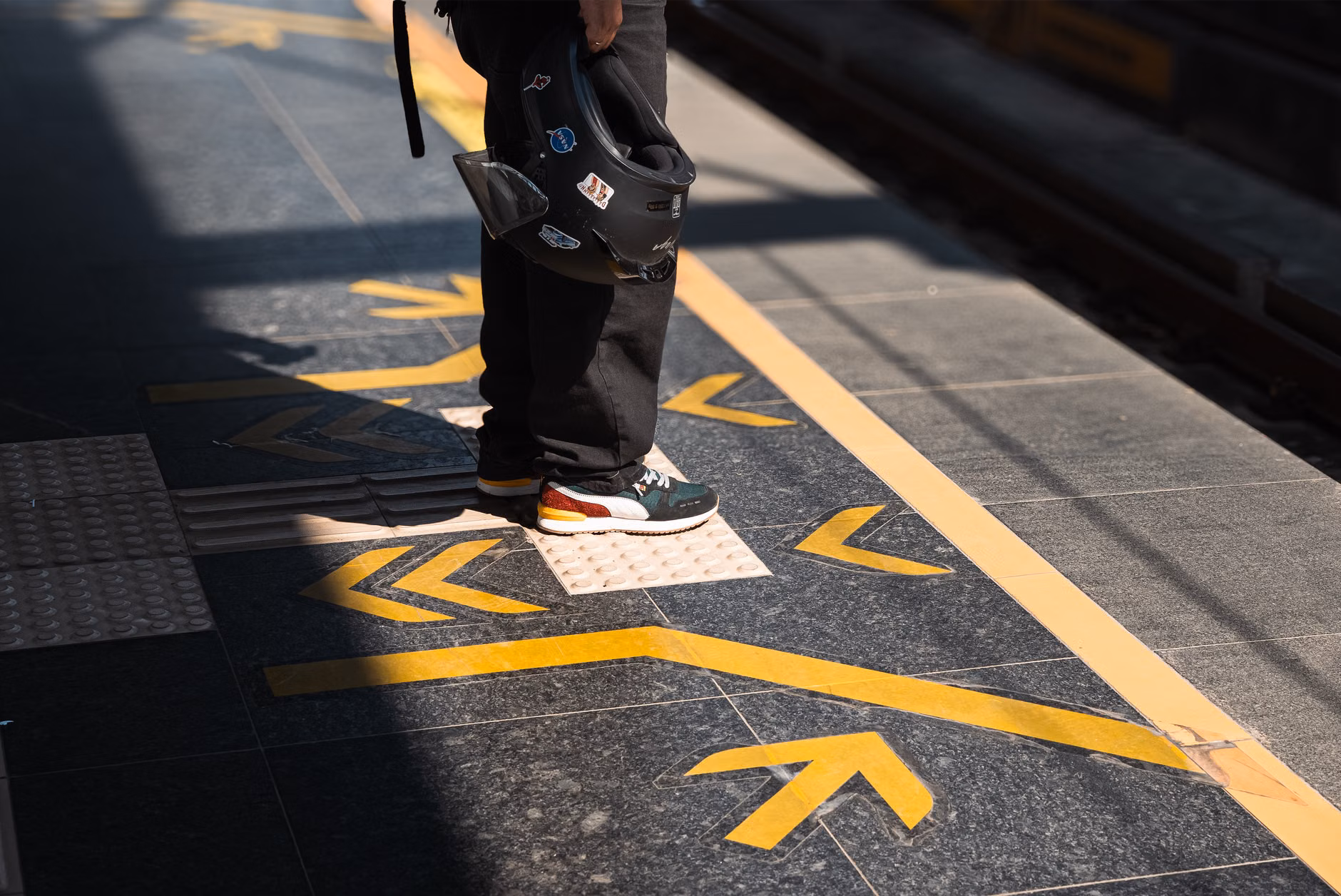 An elderly person walking safely along a flat, well-marked station corridor.