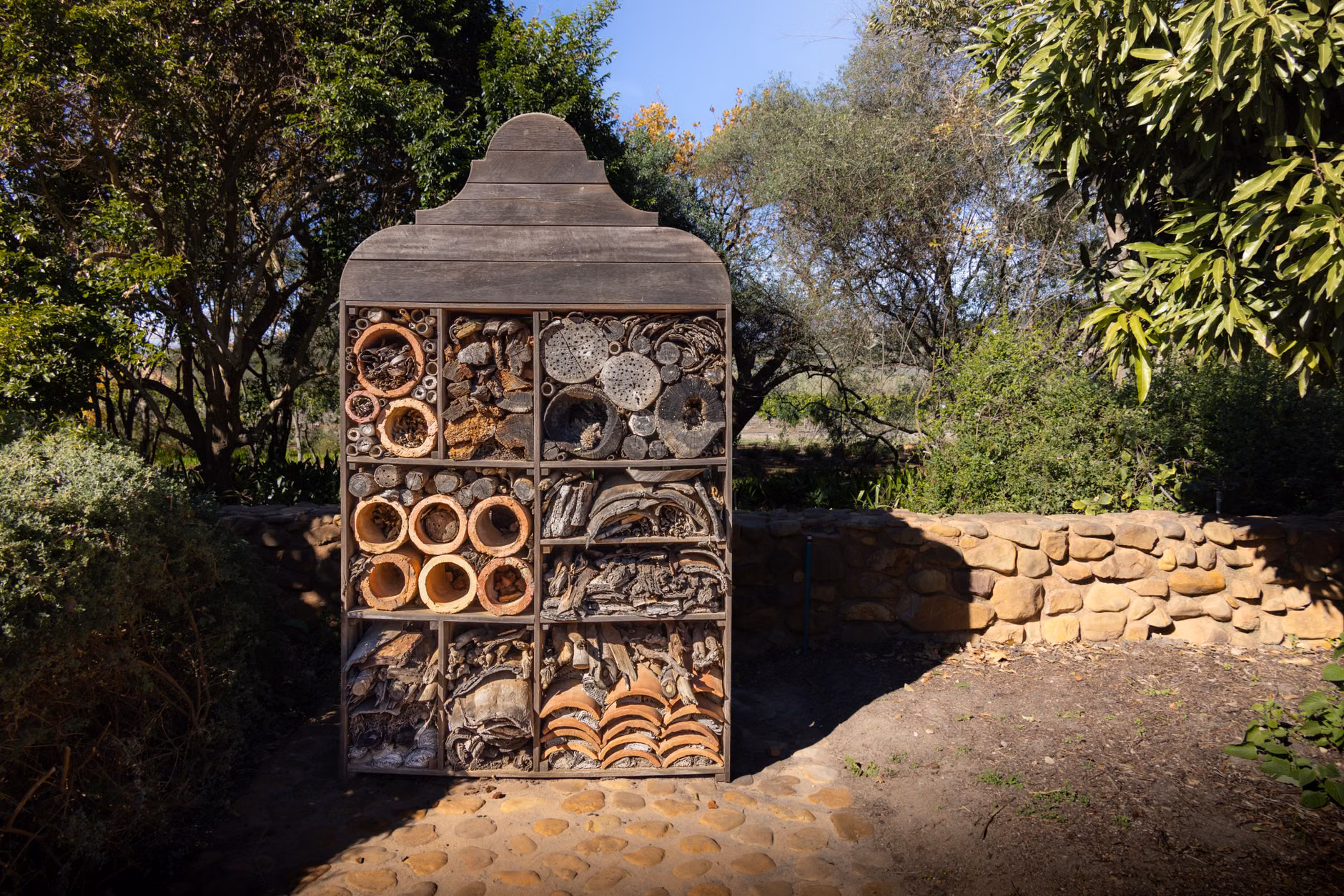 A simple wooden insect hotel mounted on a garden wall.