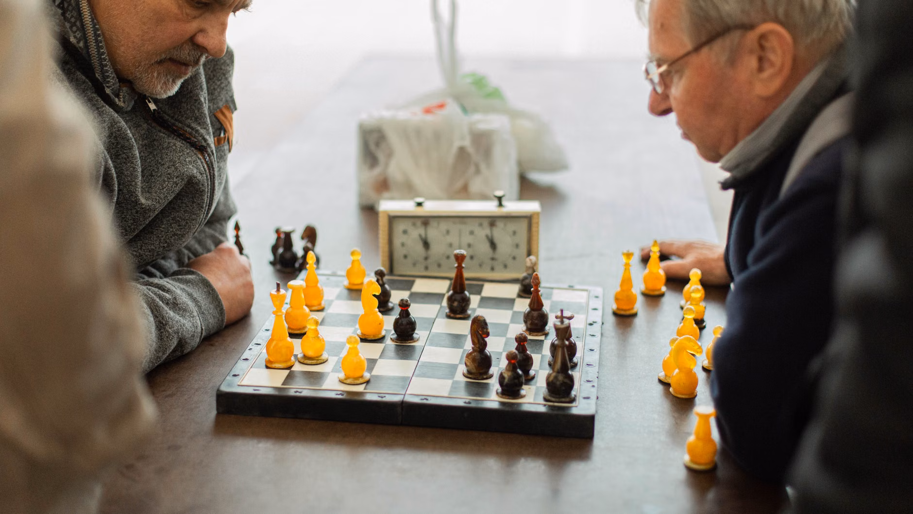 Beyond the Board: The Hidden Social and Cognitive Power of Local Chess Clubs 3 Two seniors discussing a chess strategy over a board.