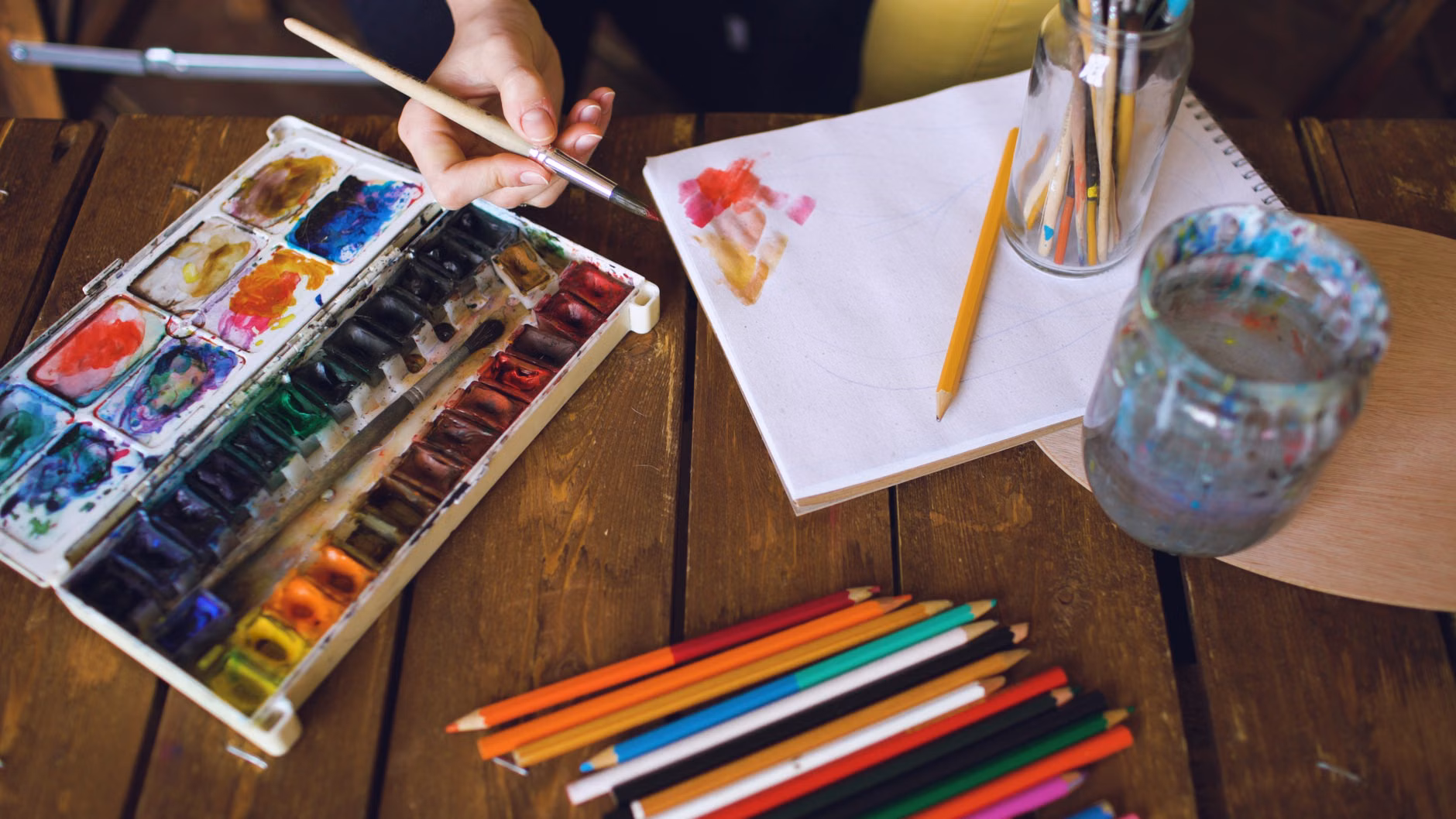An organized setup of watercolor painting materials on a wooden table.