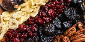 A vibrant assortment of Vitamin E-rich foods like nuts, seeds, and fresh vegetables on a wooden surface.