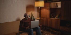An older adult wearing noise-canceling headphones in an airport lounge.