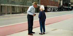 An older couple safely crossing a modern, accessible city street with clear pedestrian signals.