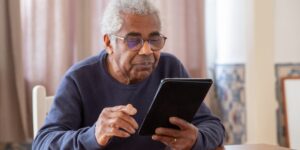 An older adult using a tablet with accessibility settings in a bright, modern room.