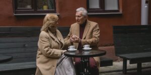 An elderly couple enjoying a coffee at a cafe in a historic plaza.