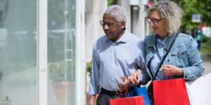 An active senior couple walking through a sunny city street with lightweight gear.
