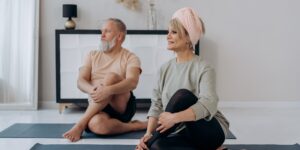 A senior couple practicing seated hip abduction for stability in a bright living room.