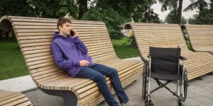 Modern, accessible park seating in a green, sunlit urban park setting.