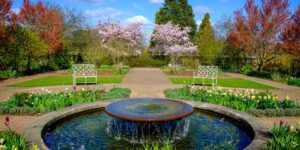 A scenic, accessible botanical garden path with benches and flowers.