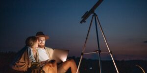 An older couple engaging in amateur astronomy in a quiet field at night.