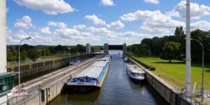 A modern river cruise ship entering a historic stone lock chamber.