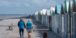 A senior couple enjoying a walk on a coastal boardwalk during sunset.