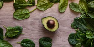 A selection of magnesium-rich whole foods including spinach, seeds, and nuts on a wooden table.