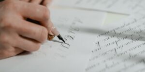 Close-up of an older adult practicing calligraphy with a fountain pen on parchment.