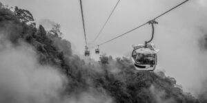 A modern, accessible cable car cabin moving over a scenic city during sunset.