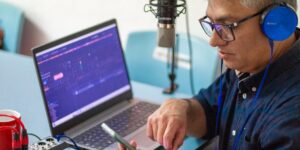 An older adult recording their voice in a professional home studio setup.