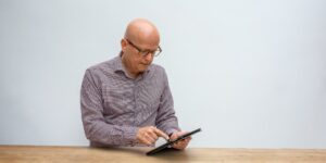 A senior adult using a tablet in a modern, secure home environment.