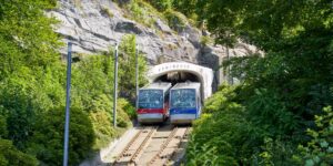A scenic view of a modern funicular ascending a mountain toward a historic city.