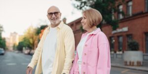 An active senior couple exploring a city while using discreet audio technology.