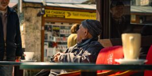 An elderly couple enjoying coffee at an accessible outdoor cafe in a historic plaza.