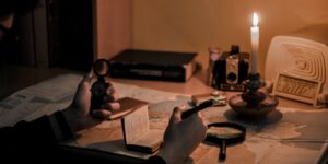 An older adult studying a map with a compass and magnifying glass at a desk.