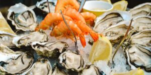 A selection of zinc-rich foods like oysters, pumpkin seeds, and lean beef on a wooden table.