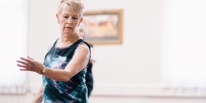 An active senior performing finger-tapping exercises at a table.