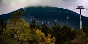 A scenic view of a modern, accessible cable car ascending a mountain.