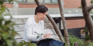 An older adult sketching birds in a park during a peaceful morning.