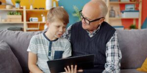 An older adult enjoying digital storytelling on a tablet in a bright, comfortable home.