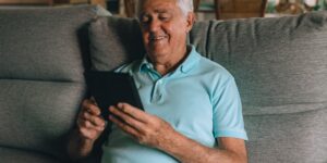 A senior man relaxing in a safe, smart-enabled living room with a voice assistant device.
