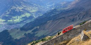 A scenic view of an accessible funicular climbing a mountain towards a historic town.