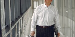 A confident senior traveler walking through a modern airport terminal.