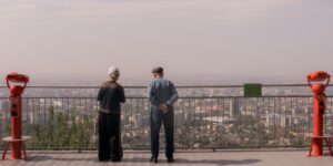 A senior couple using a telescope on a quiet terrace under a starry night sky.