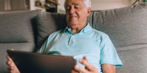 A senior adult using a digital health portal on a tablet at home.