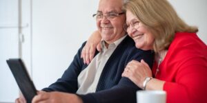 A senior couple reviewing digital health information on a tablet in a well-lit room.