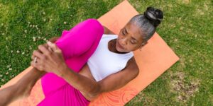 An older adult performing seated leg exercises in a sunlit living room to improve circulation.