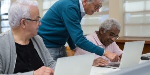 A diverse group of older adults collaborating on a repair project at a community workshop.