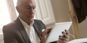 A senior adult using a digital tablet in a modern, well-lit public library.