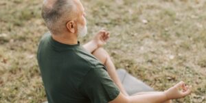 A senior man practicing seated posture and glute exercises in a sunlit living room.