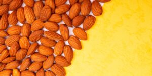 A selection of Vitamin E-rich whole foods like almonds, seeds, and greens on a wooden table.