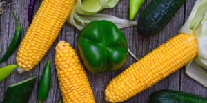 A variety of fresh green vegetables on a wooden table representing a healthy diet.